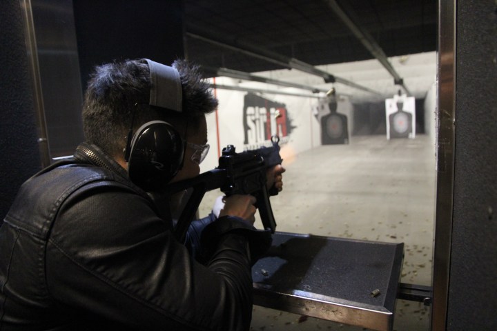 Person in a shooting range aiming a gun at targets.