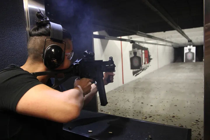 Person shooting a rifle at an indoor gun range target.