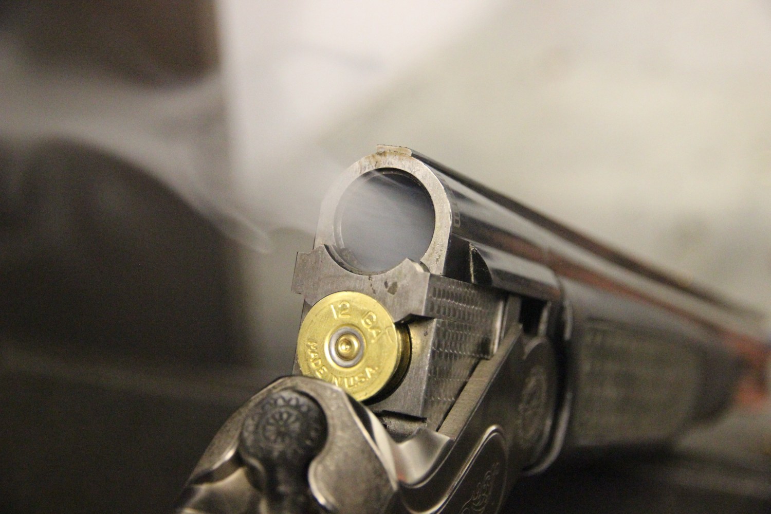Close-up of an open shotgun with smoke near the barrel.