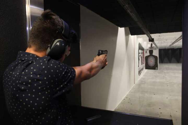 Person aiming a handgun at a target in an indoor shooting range.